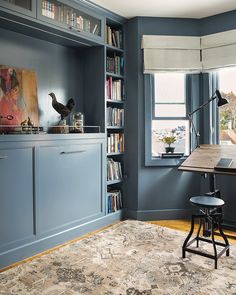 a room with blue walls and bookshelves in the corner, an area rug on the floor