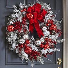 a christmas wreath with red and silver ornaments hanging on the front door to give it a festive feel