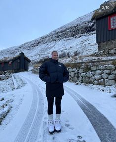 a woman standing on the side of a snow covered road