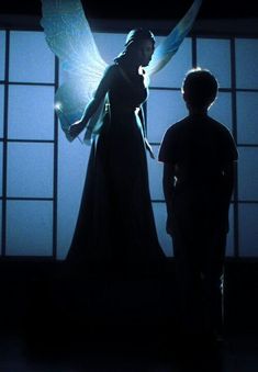 a man standing next to a woman in front of a window with an angel on it