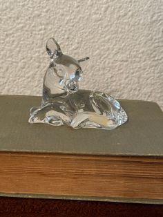 a glass dog figurine sitting on top of a book next to a wall