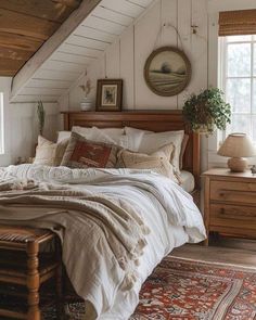 an attic bedroom with white walls and wooden beams, bedding, rugs and windows