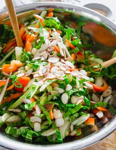 a salad with carrots, celery, onions and almonds in a silver bowl