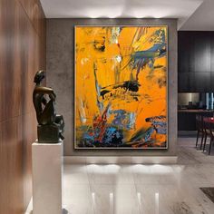 an abstract painting hangs on the wall next to a statue in a modern living room