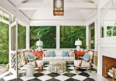 a living room with checkered flooring and white furniture in front of large windows