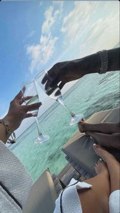 two people toasting with wine glasses in front of the ocean