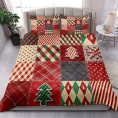 a bed covered in red and green quilts with christmas trees on them, next to a window