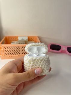 a hand is holding a small crocheted case with an earphone in it