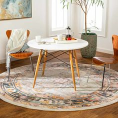 a round table with two chairs and a potted plant in the corner on top