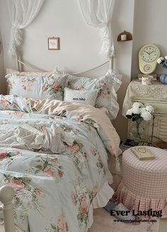 a bed with floral comforter and pillows in a bedroom next to a dresser, mirror and clock