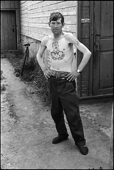 black and white photograph of a man standing in front of a building with his hands on his hips