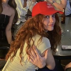 a woman in a red hat is sitting at a table with other people around her