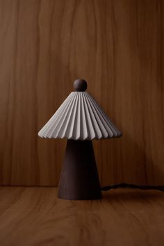 a white lamp sitting on top of a wooden table next to a wood paneled wall