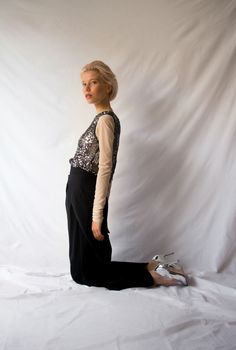 a woman sitting on the ground in front of a white backdrop