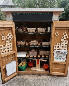 an open wooden cabinet with baskets and other items in it's back door area