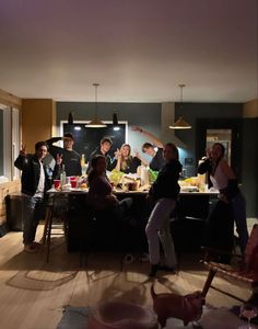 a group of people standing around a kitchen counter with food on the table in front of them