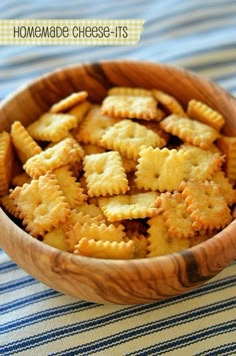 a wooden bowl filled with crackers on top of a blue and white table cloth