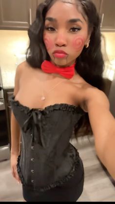 a woman in a black corset and red bow tie is taking a selfie