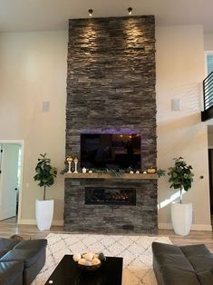 a living room with couches and a large stone fireplace in the middle of it