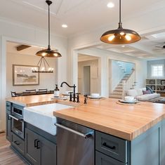 a kitchen with an island, sink and dishwasher next to a living room