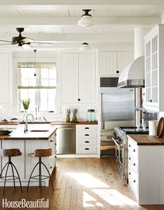 a kitchen with white cabinets and wood flooring next to an island in the middle