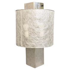 a lamp that is sitting on top of a white surface with a silver shade over it