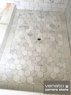 a shower with hexagonal tiles and a hole in the floor