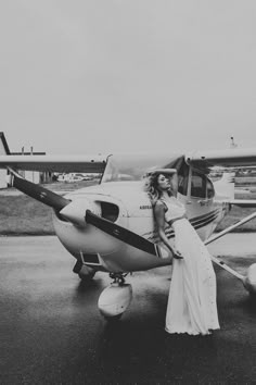 a couple kissing in front of an airplane on the tarmac with another plane behind them