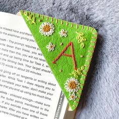 an open book with embroidered letters and flowers on it