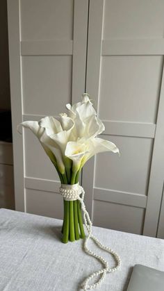 a bouquet of white flowers on a table with pearls and a macbook in the background