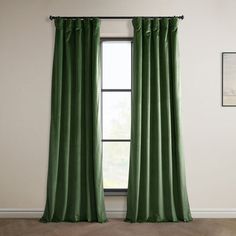 a green curtain hanging in front of a window with a wooden floor and framed pictures on the wall