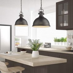 a kitchen with two pendant lights hanging over the island