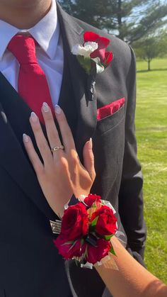 a man in a suit and red tie with his hand on the woman's lapel