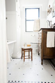 a white bathroom with black and white floor tiles