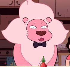 the pink bear is wearing a bow tie and standing in front of a kitchen counter