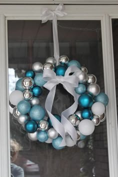 a blue and silver christmas ornament wreath on a window sill with white ribbon