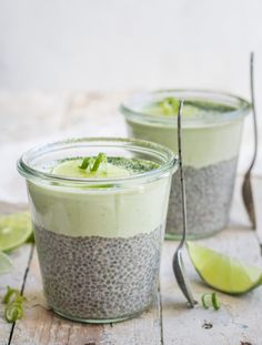 two glasses filled with chia pudding on top of a wooden table next to lime wedges