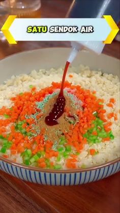 a bowl filled with rice and carrots on top of a wooden table next to a sign