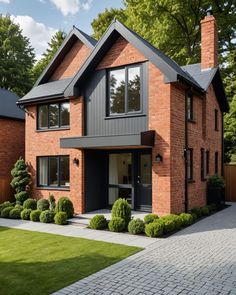 a brick house with black trim on the front and side windows, surrounded by green grass