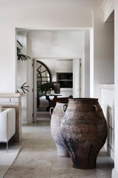 two large vases sitting on top of a tiled floor next to a white couch