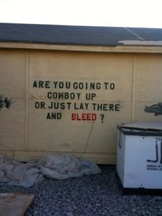 a sign on the side of a building that says, are you going to cowboy up or just lay there and bleed?