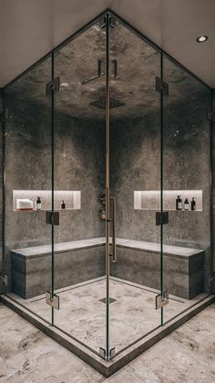 a glass walled bathroom with two sinks and a bathtub in the middle, surrounded by marble flooring