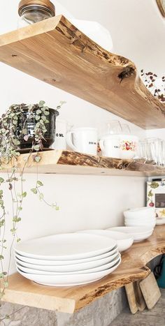 plates and bowls are stacked on wooden shelves