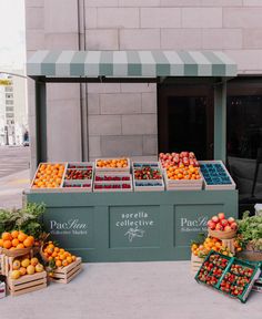 an outdoor fruit stand with oranges, apples and other fruits on display in boxes