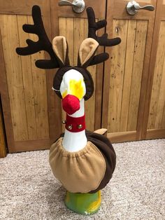 a stuffed turkey wearing a reindeer hat on top of a green stand in front of wooden doors