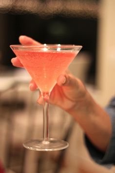 a person holding a wine glass in their hand with a pink substance on the rim