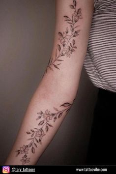 a woman's arm with flowers and leaves on it