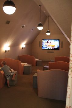 a man sitting in an orange chair watching tv