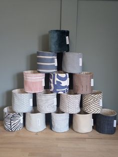 many different colored baskets stacked on top of each other in front of a gray wall