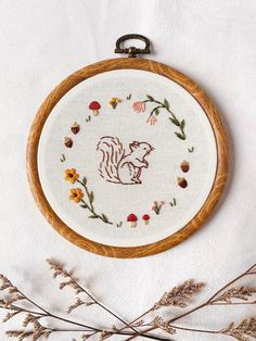 an embroidered squirrel on a white background with dried flowers